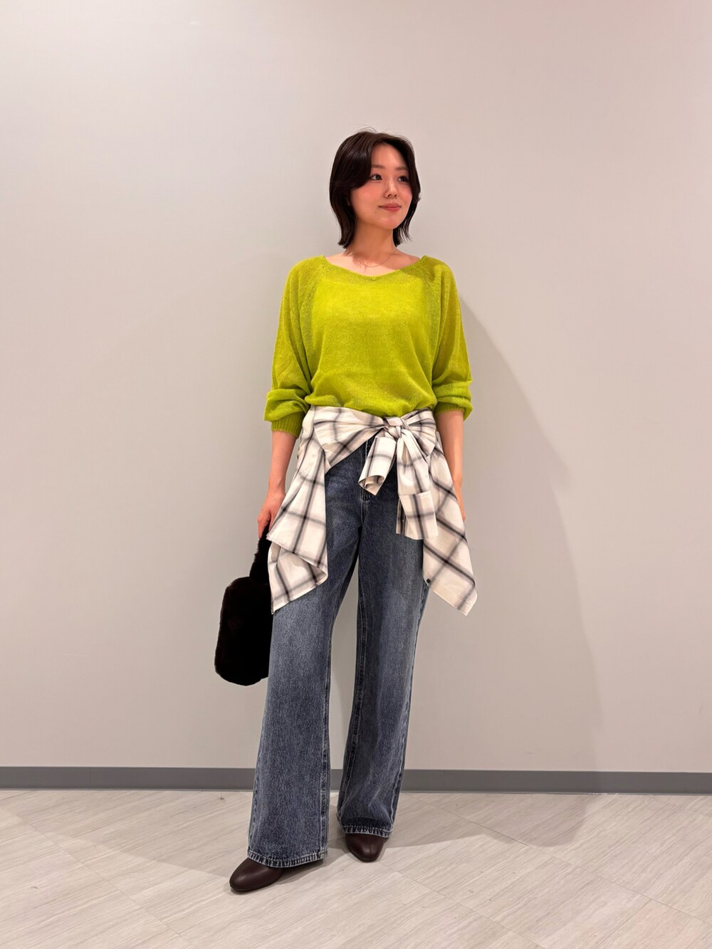グリーン系のニット/セーター、ホワイト系のシャツ/ブラウス、ブルー系のデニムパンツを着用したレディースの秋コーディネートの2枚目の写真