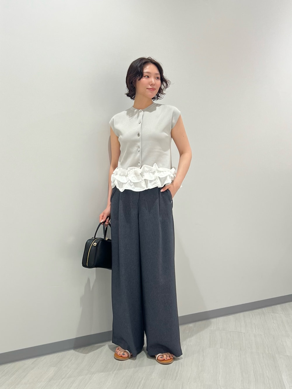 グレー系のベスト、ブルー系のその他パンツ、ブラック系のボストンバッグを着用したレディースの夏コーディネートの2枚目の写真