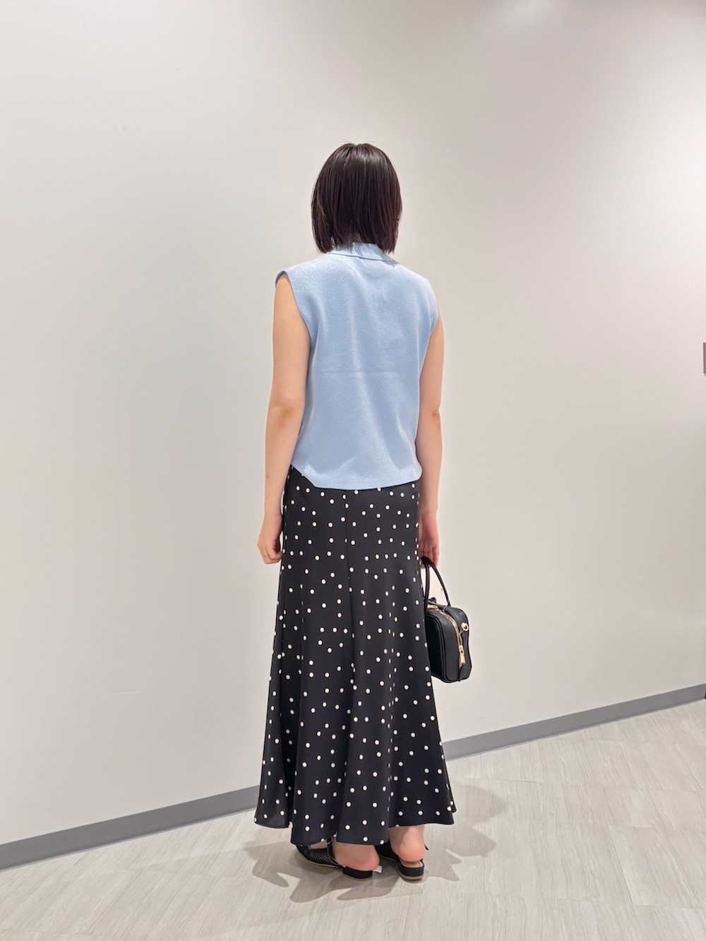 ブルー系のポロシャツ、ブラック系のスカート、ブラック系のボストンバッグを着用したレディースの夏コーディネートの3枚目の写真