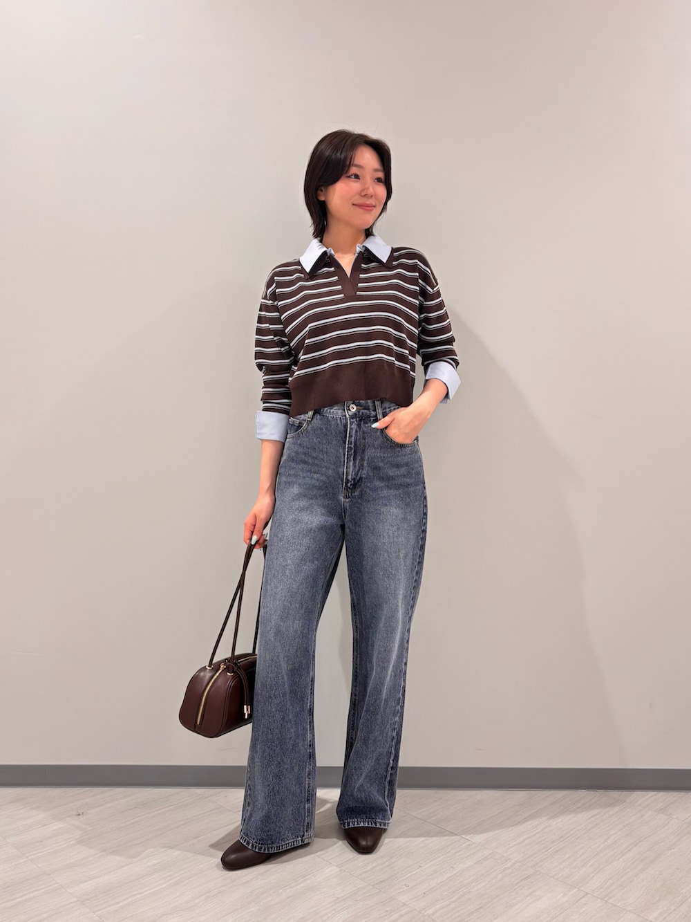 ブラウン系のニット/セーター、ブルー系のデニムパンツ、ブラック系のボストンバッグを着用したレディースの秋コーディネートの2枚目の写真