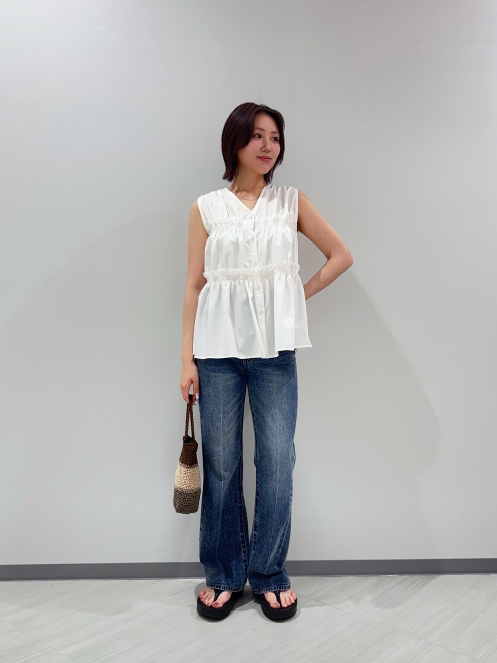ホワイト系のシャツ/ブラウス、ブルー系のデニムパンツ、ゴールド系のハンドバッグを着用したレディースの夏コーディネートの2枚目の写真