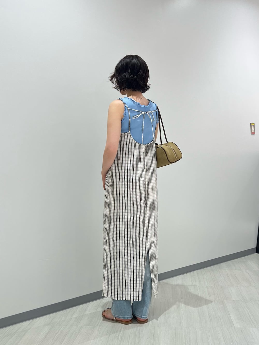 ブルー系のタンクトップ、ブルー系のデニムパンツ、ホワイト系のワンピースを着用したレディースの夏コーディネートの3枚目の写真
