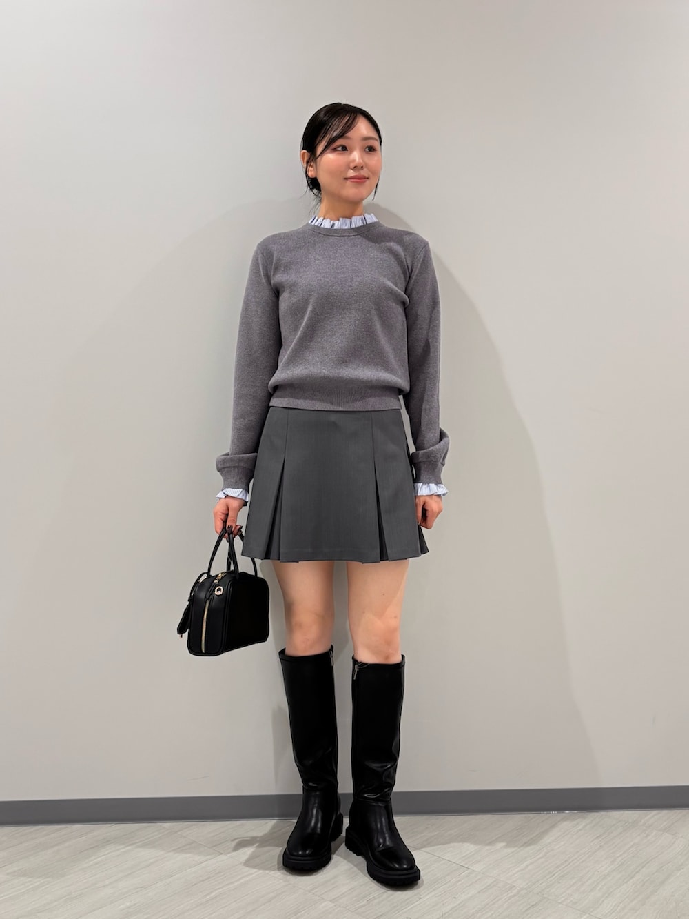 グレー系のニット/セーター、グレー系のスカート、ブラック系のボストンバッグを着用したレディースの秋コーディネートの3枚目の写真