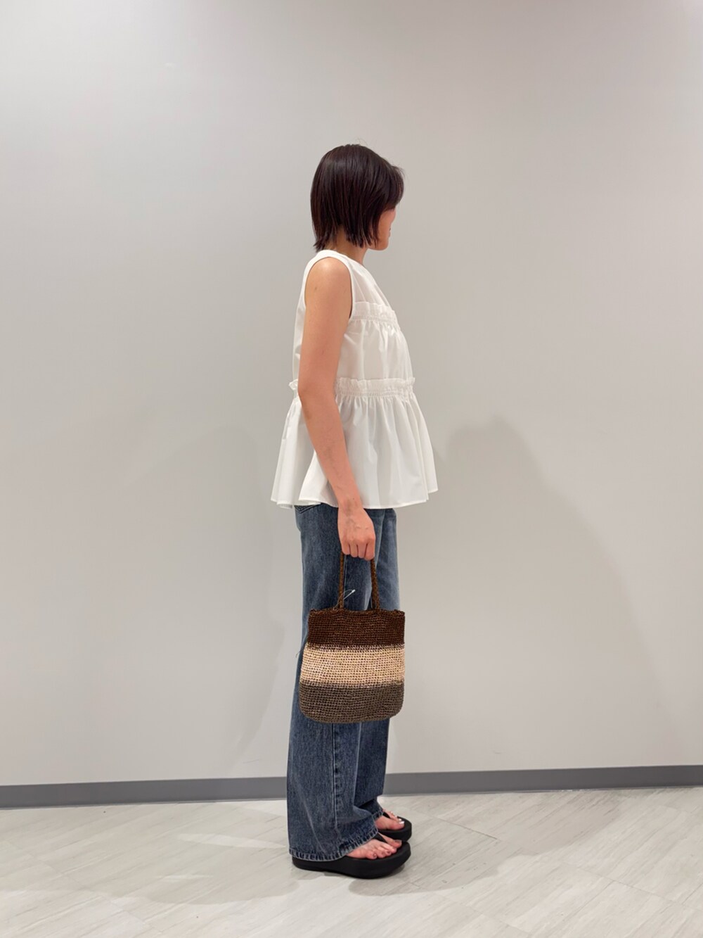 ホワイト系のシャツ/ブラウス、ブルー系のデニムパンツ、ゴールド系のハンドバッグを着用したレディースの夏コーディネートの3枚目の写真