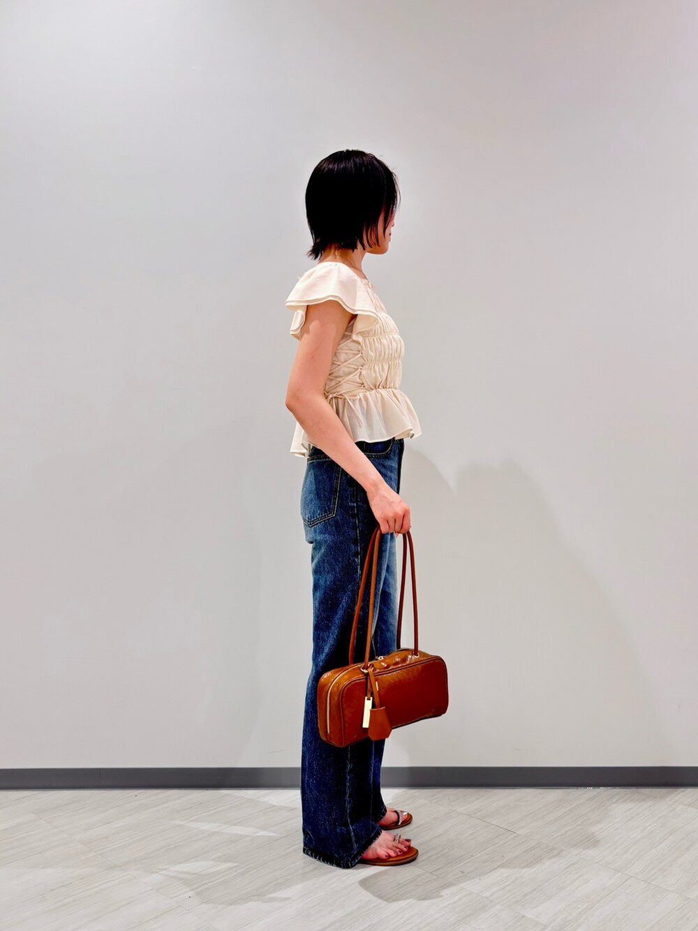 ホワイト系のシャツ/ブラウス、ブルー系のデニムパンツ、オレンジ系のボストンバッグを着用したレディースの夏コーディネートの2枚目の写真