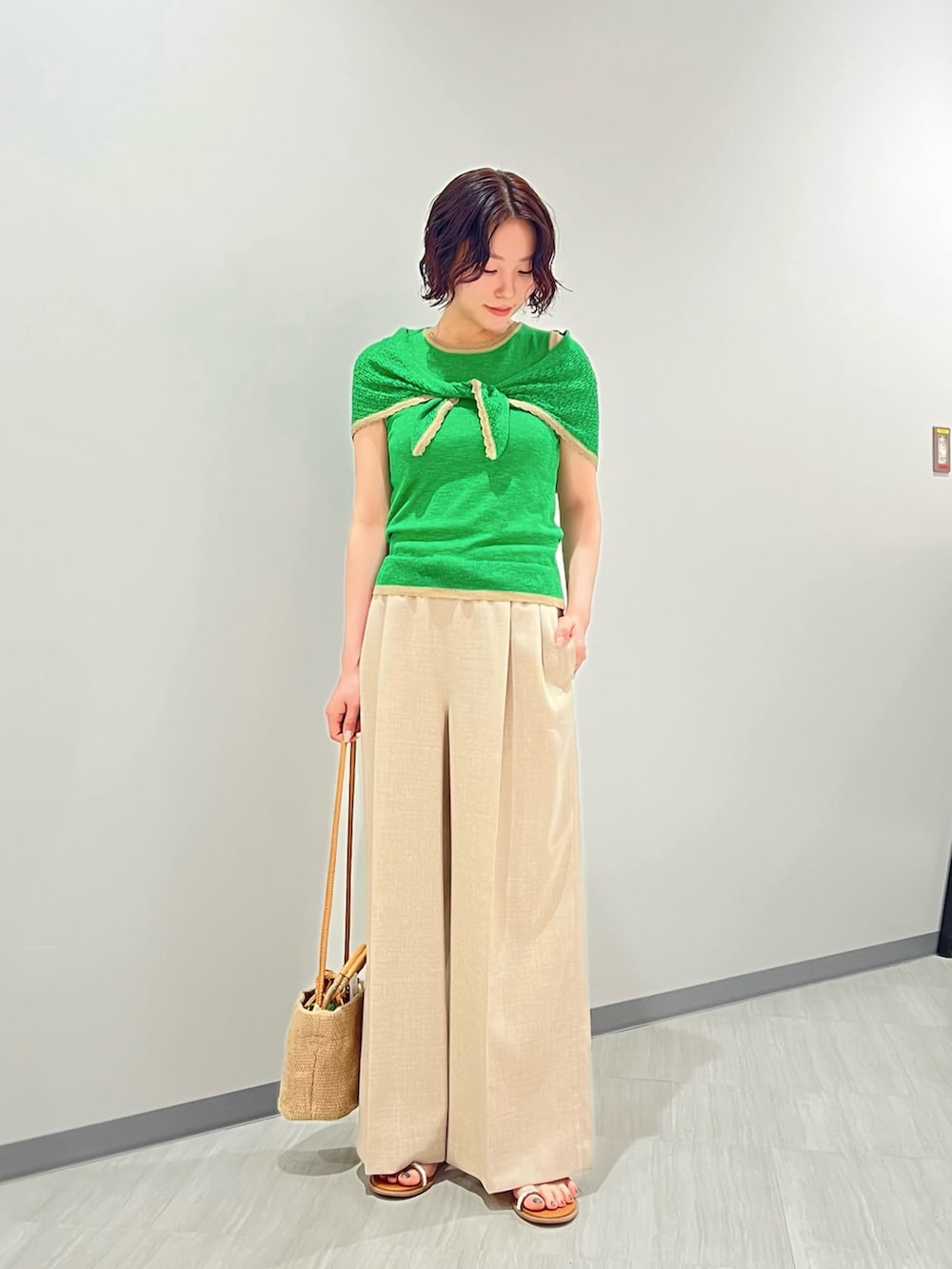 グリーン系のニット/セーター、ベージュ系のパンツ、ベージュ系のショルダーバッグを着用したレディースの夏コーディネートの2枚目の写真