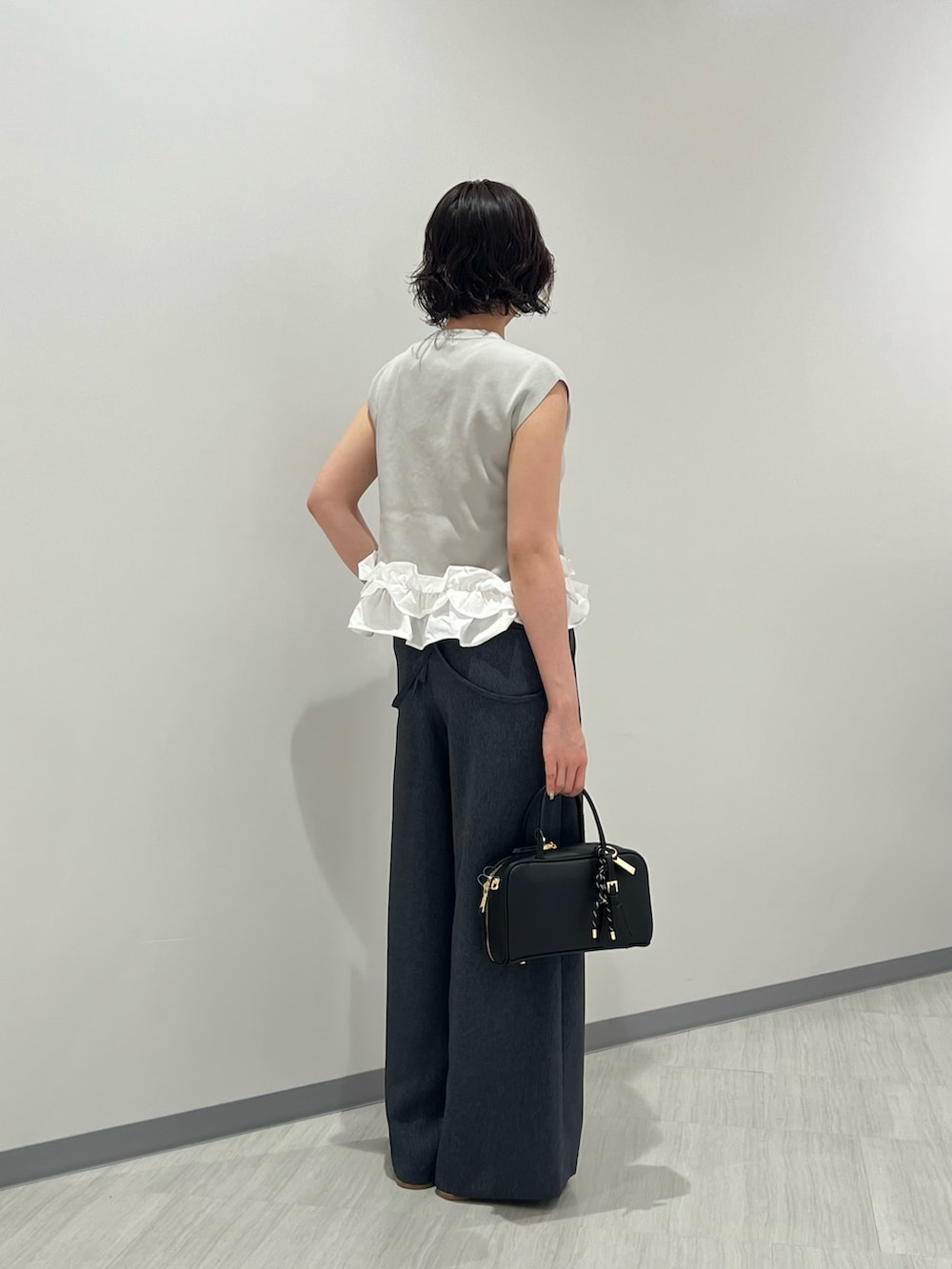 グレー系のベスト、ブルー系のその他パンツ、ブラック系のボストンバッグを着用したレディースの夏コーディネートの3枚目の写真