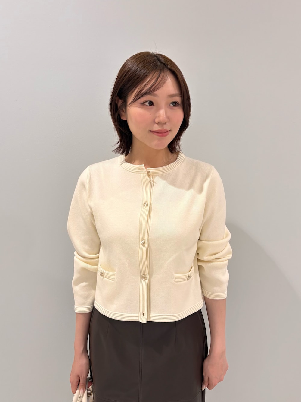 ホワイト系のカーディガン/ボレロ、ブラウン系のスカート、ブラウン系のブーツを着用したレディースの秋コーディネートの4枚目の写真