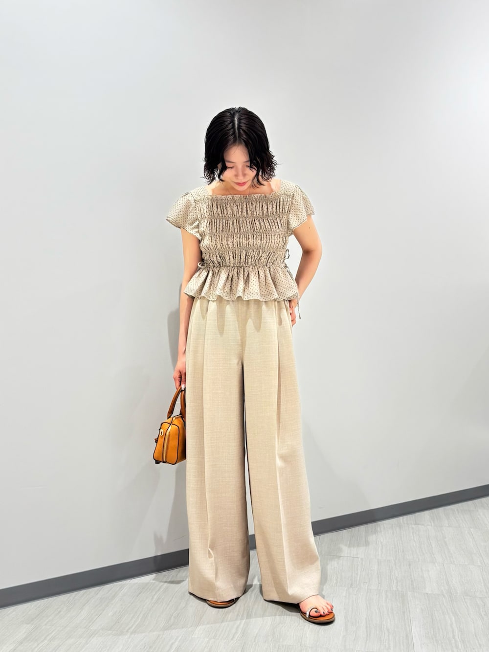 ベージュ系のシャツ/ブラウス、ベージュ系のその他パンツ、オレンジ系のボストンバッグを着用したレディースの夏コーディネートの2枚目の写真