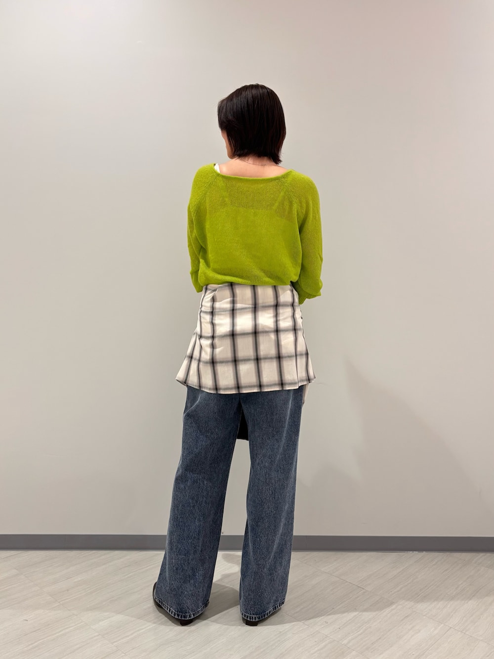 グリーン系のニット/セーター、ホワイト系のシャツ/ブラウス、ブルー系のデニムパンツを着用したレディースの秋コーディネートの4枚目の写真