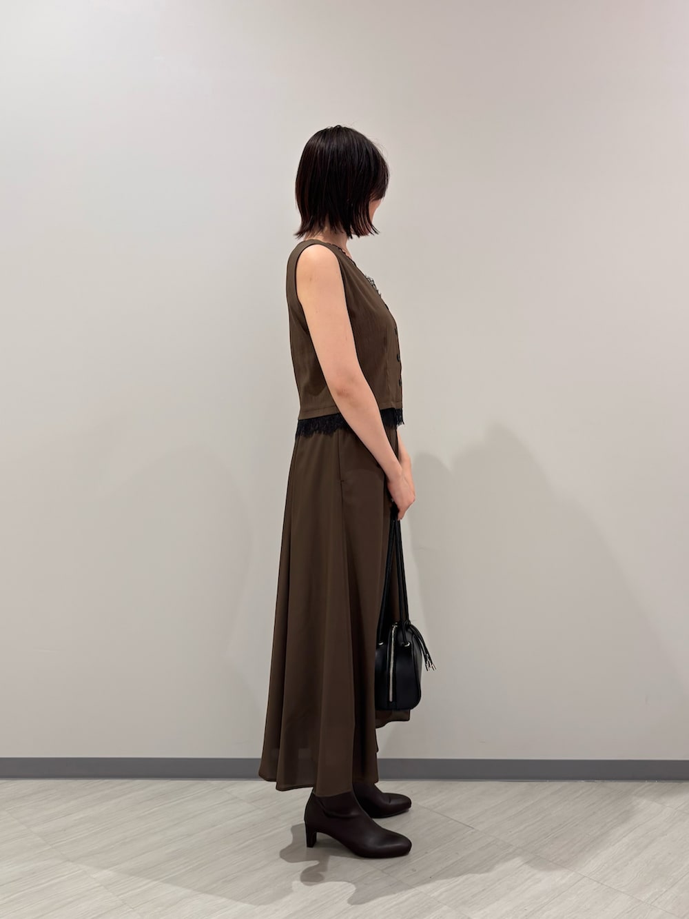 ブラウン系のワンピース、ブラウン系のブーツ、ブラック系のボストンバッグを着用したレディースの夏コーディネートの3枚目の写真