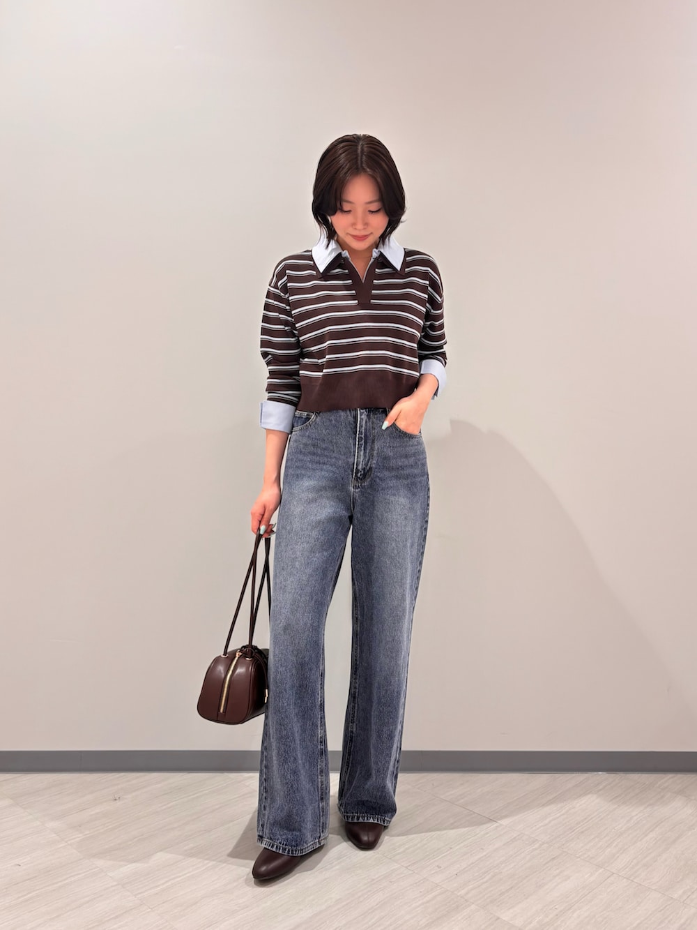 ブラウン系のニット/セーター、ブルー系のデニムパンツ、ブラック系のボストンバッグを着用したレディースの秋コーディネートの3枚目の写真