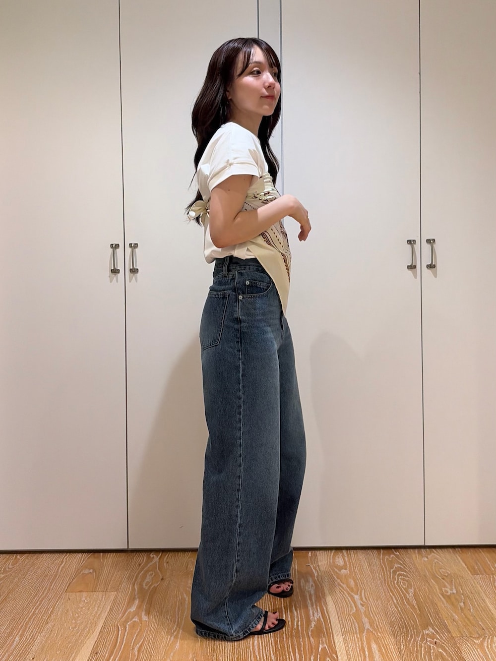 ブルー系のデニムパンツ、ホワイト系のTシャツ/カットソー、ベージュ系のバンダナ/スカーフを着用したレディースの夏コーディネートの2枚目の写真