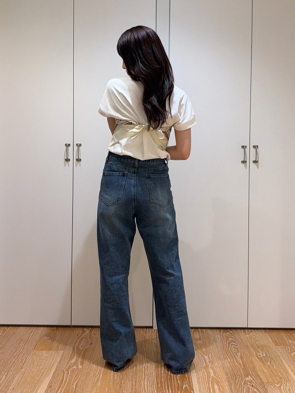 ブルー系のデニムパンツ、ホワイト系のTシャツ/カットソー、ベージュ系のバンダナ/スカーフを着用したレディースの夏コーディネートの3枚目の写真