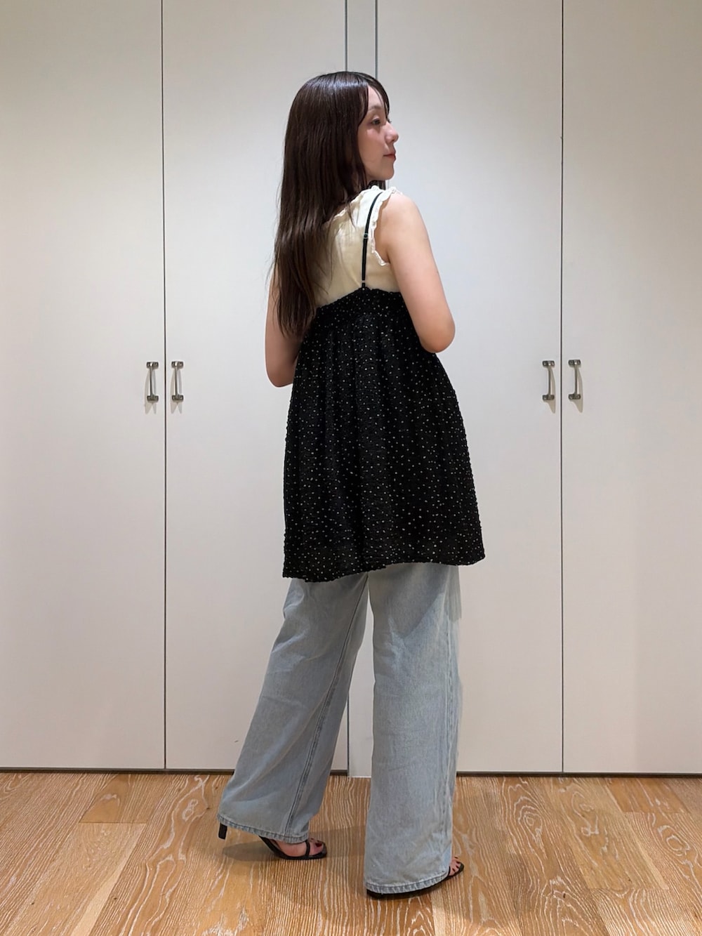 ブラック系のキャミソール、ホワイト系のタンクトップ、ブルー系のデニムパンツを着用したレディースの夏コーディネートの2枚目の写真