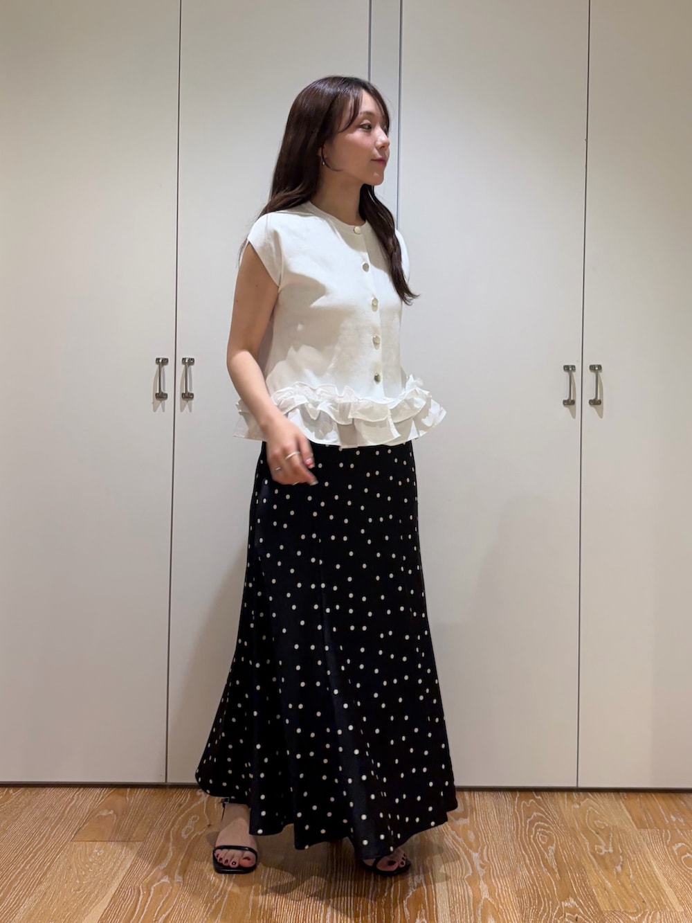 ブラック系のスカート、ホワイト系のベストを着用したレディースの夏コーディネートの2枚目の写真