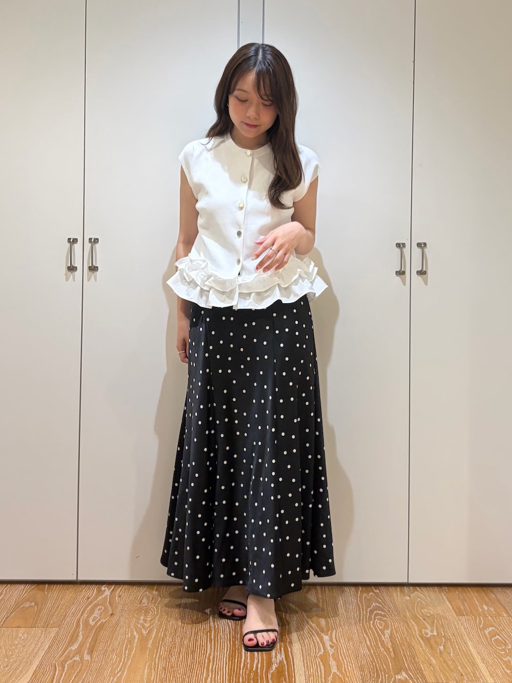 ブラック系のスカート、ホワイト系のベストを着用したレディースの夏コーディネートの4枚目の写真