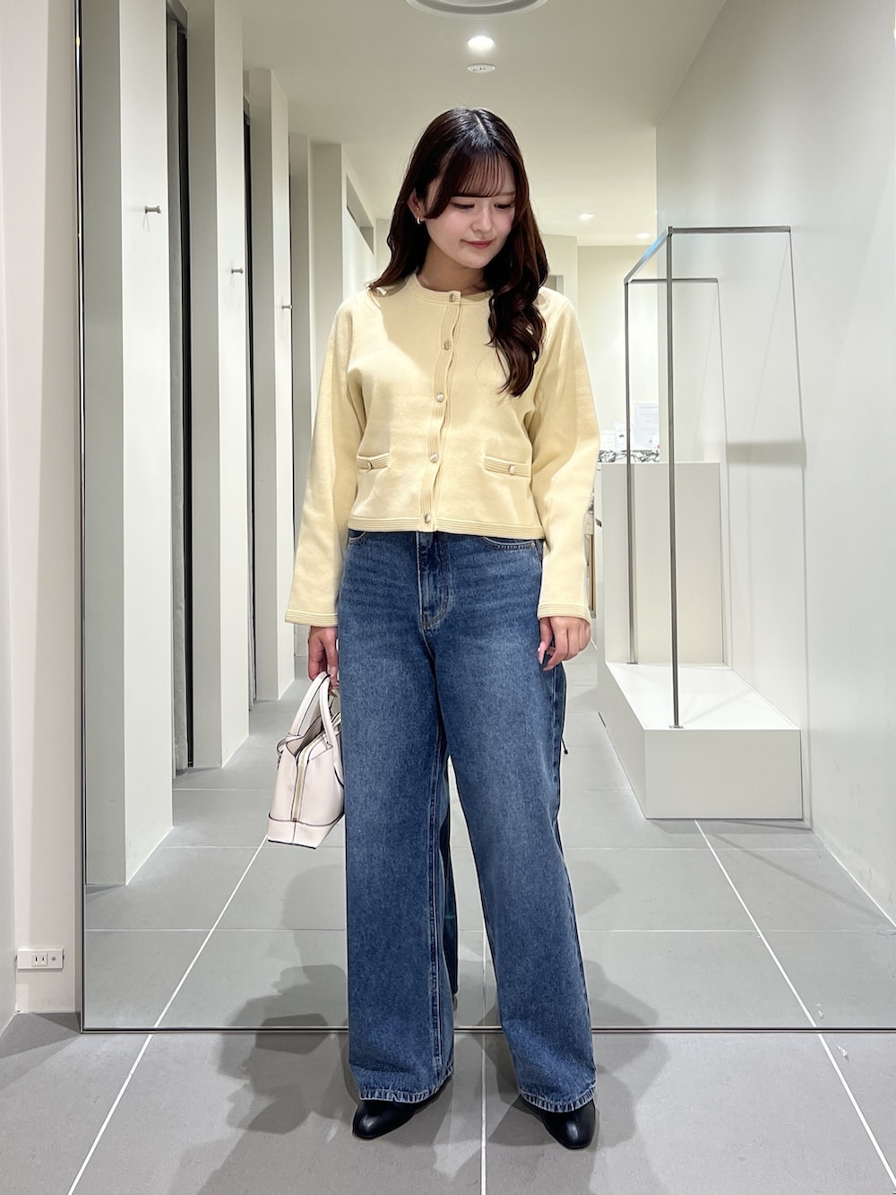 イエロー系のカーディガン/ボレロ、ブルー系のデニムパンツ、ホワイト系のトートバッグを着用したレディースの夏コーディネートの3枚目の写真