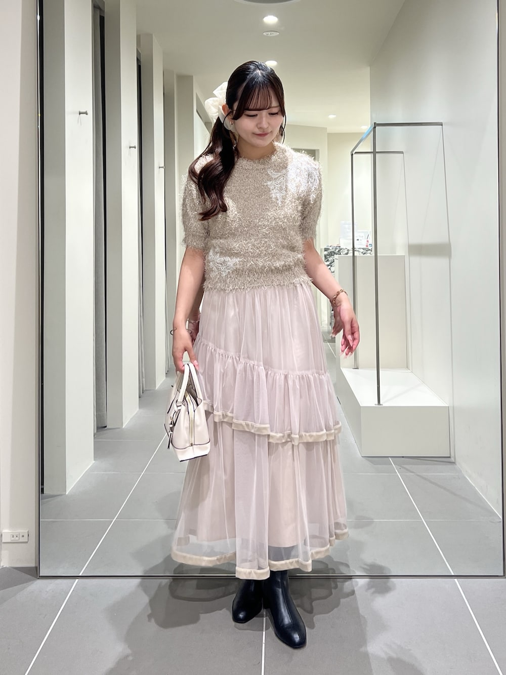 ベージュ系のニット/セーター、ベージュ系のスカート、ホワイト系のトートバッグを着用したレディースの夏コーディネートの2枚目の写真