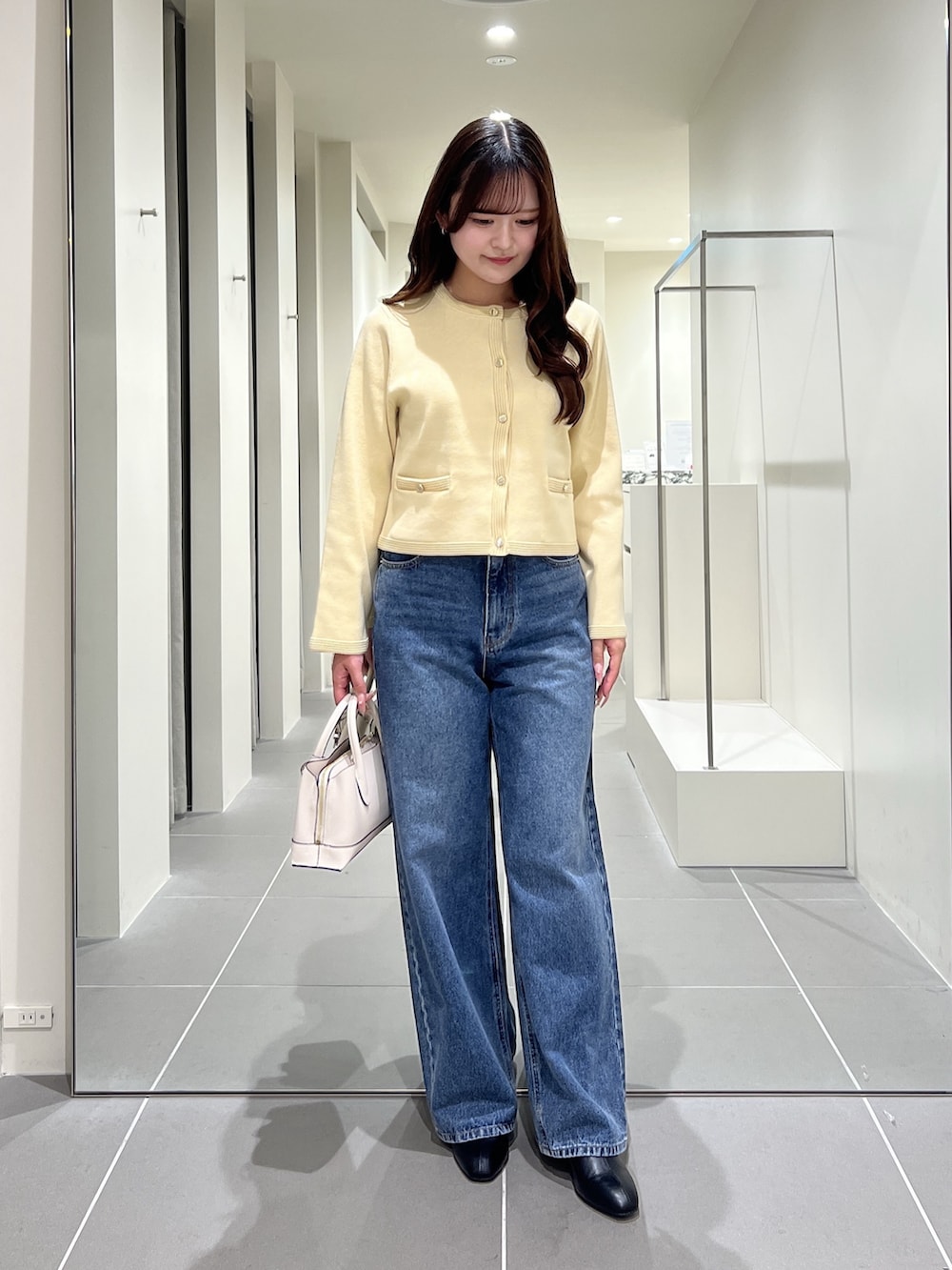 イエロー系のカーディガン/ボレロ、ブルー系のデニムパンツ、ホワイト系のトートバッグを着用したレディースの夏コーディネートの4枚目の写真