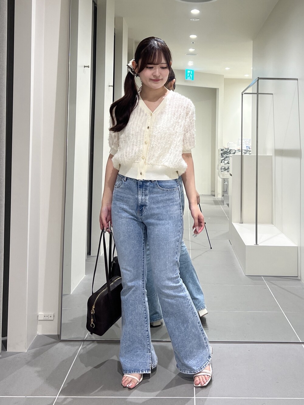 ホワイト系のカーディガン/ボレロ、ブルー系のデニムパンツ、ブラウン系のボストンバッグを着用したレディースの夏コーディネートの3枚目の写真