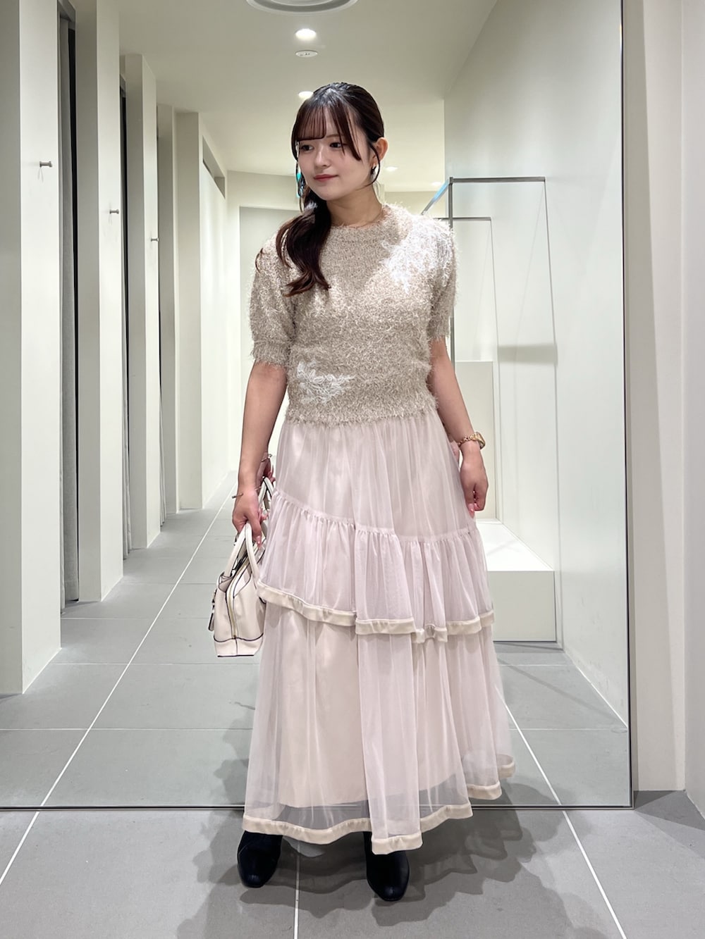 ベージュ系のニット/セーター、ベージュ系のスカート、ホワイト系のトートバッグを着用したレディースの夏コーディネートの7枚目の写真