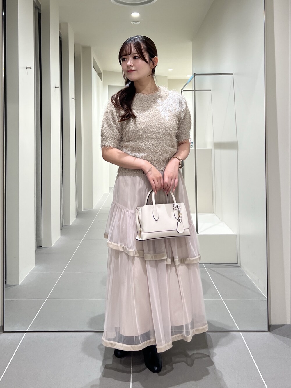 ベージュ系のニット/セーター、ベージュ系のスカート、ホワイト系のトートバッグを着用したレディースの夏コーディネートの3枚目の写真