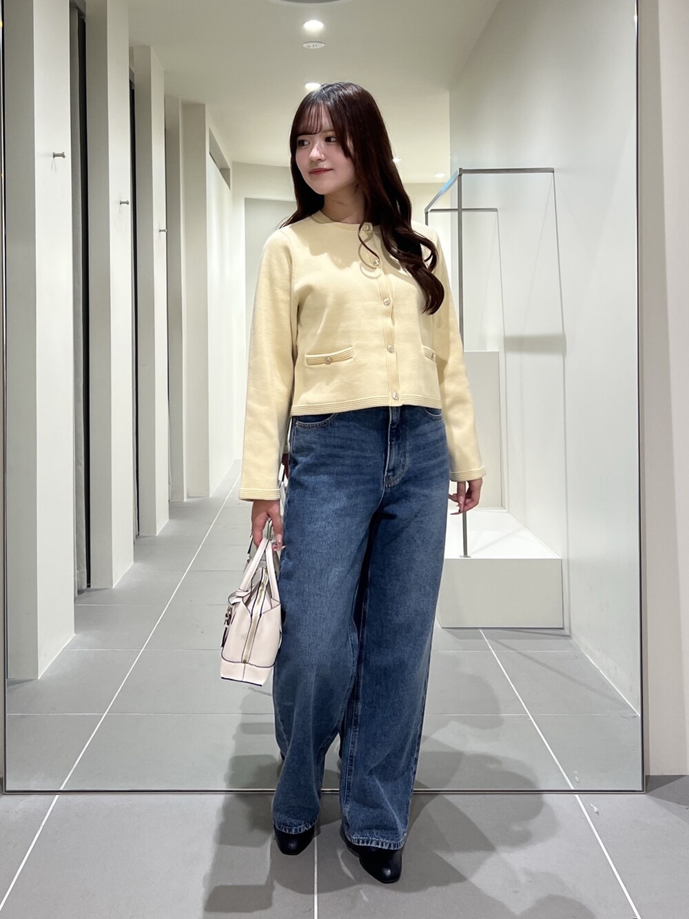 イエロー系のカーディガン/ボレロ、ブルー系のデニムパンツ、ホワイト系のトートバッグを着用したレディースの夏コーディネートの2枚目の写真