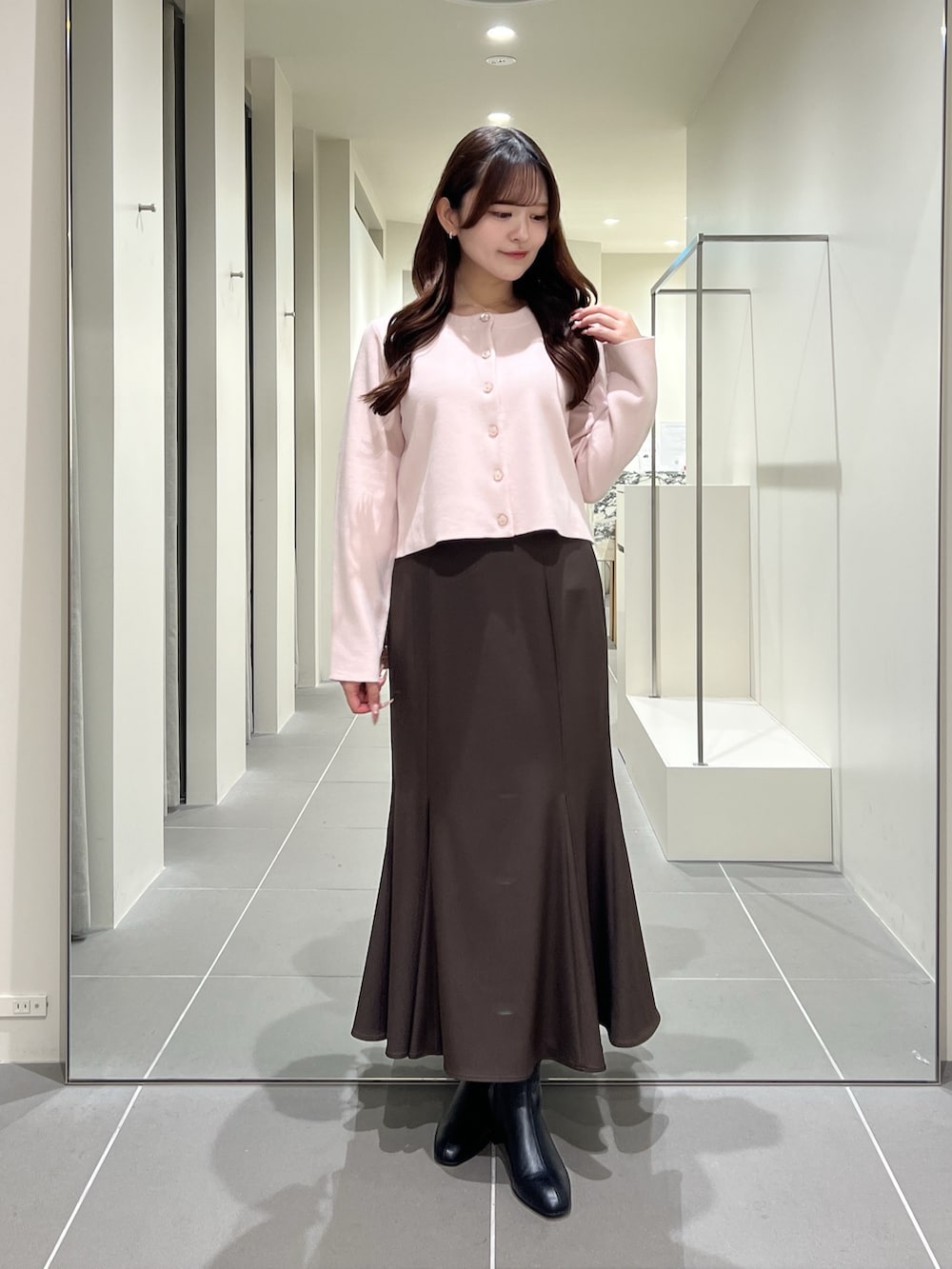 ピンク系のカーディガン/ボレロ、ブラウン系のスカート、ブラック系のブーツを着用したレディースの夏コーディネートの2枚目の写真