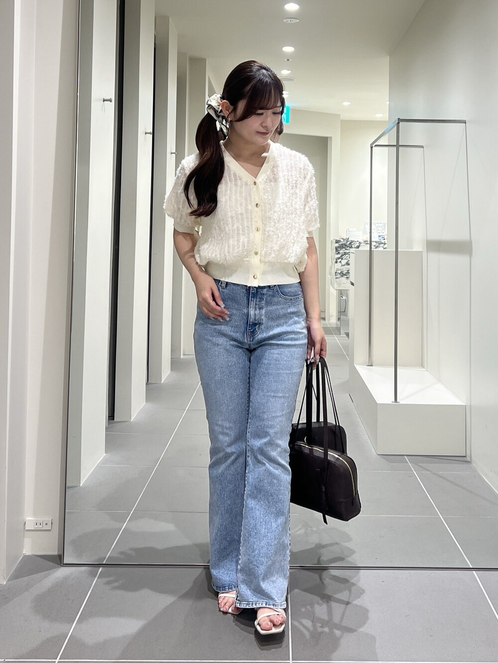 ホワイト系のカーディガン/ボレロ、ブルー系のデニムパンツ、ブラウン系のボストンバッグを着用したレディースの夏コーディネートの4枚目の写真
