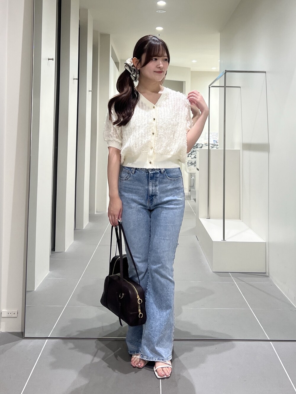 ホワイト系のカーディガン/ボレロ、ブルー系のデニムパンツ、ブラウン系のボストンバッグを着用したレディースの夏コーディネートの2枚目の写真