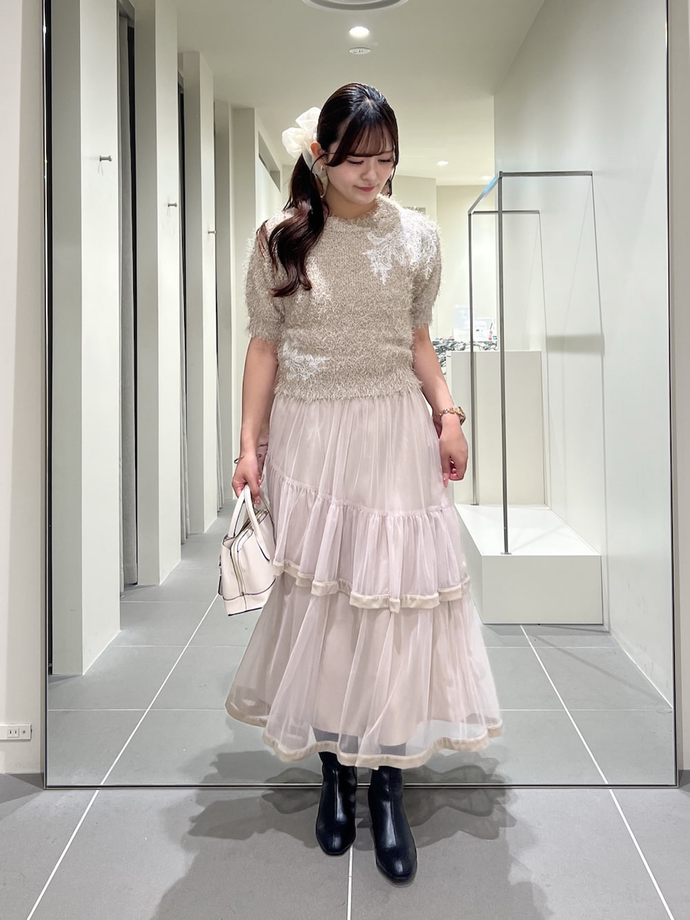 ベージュ系のニット/セーター、ベージュ系のスカート、ホワイト系のトートバッグを着用したレディースの夏コーディネートの5枚目の写真