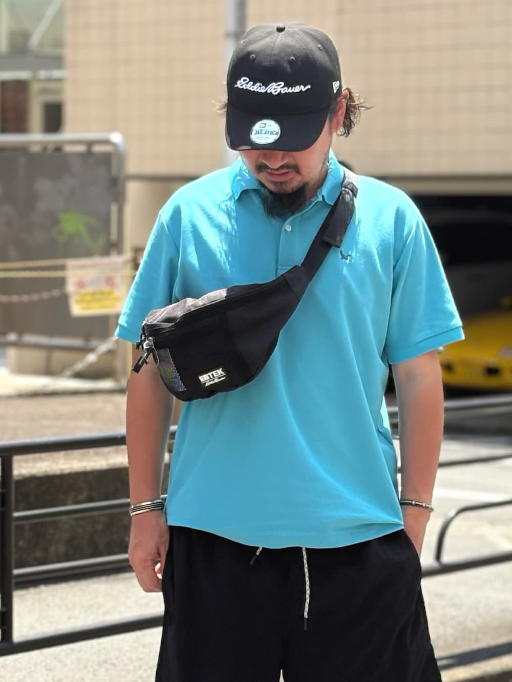 ブルー系のポロシャツ、ブラック系のボディバッグ/ウエストポーチ、ブラック系のその他パンツを着用したメンズの夏コーディネートの3枚目の写真