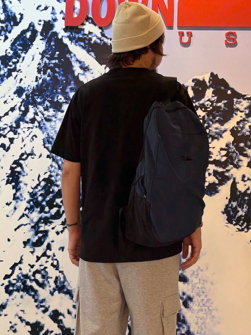 グレー系のその他パンツ、ブラック系のTシャツ/カットソー、ブルー系のバックパック/リュックを着用したメンズの夏コーディネートの2枚目の写真