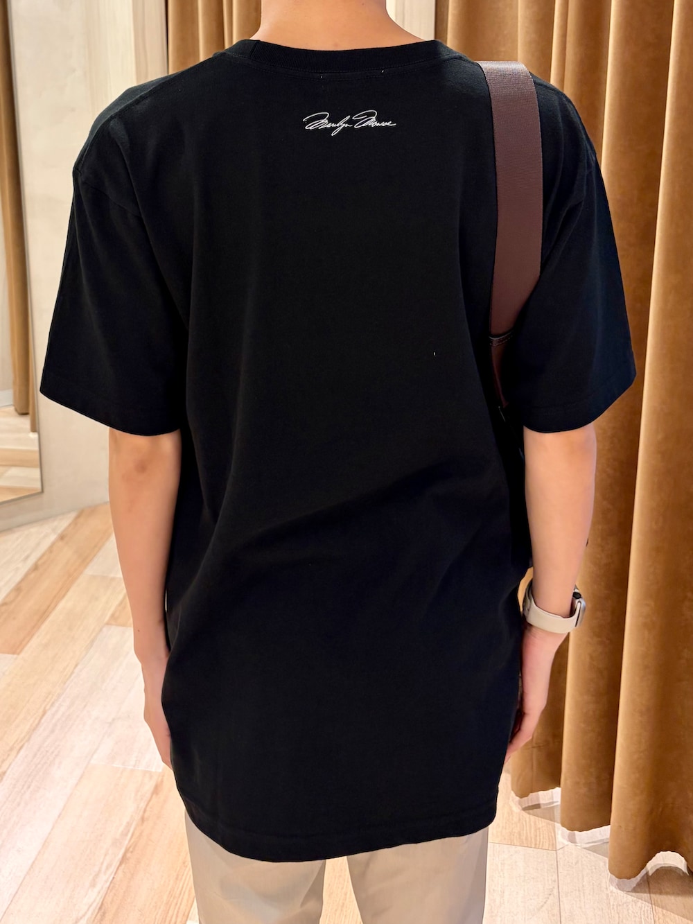 ブラック系のTシャツ/カットソー、ベージュ系のスラックス、ホワイト系のスニーカーを着用したメンズの夏コーディネートの6枚目の写真