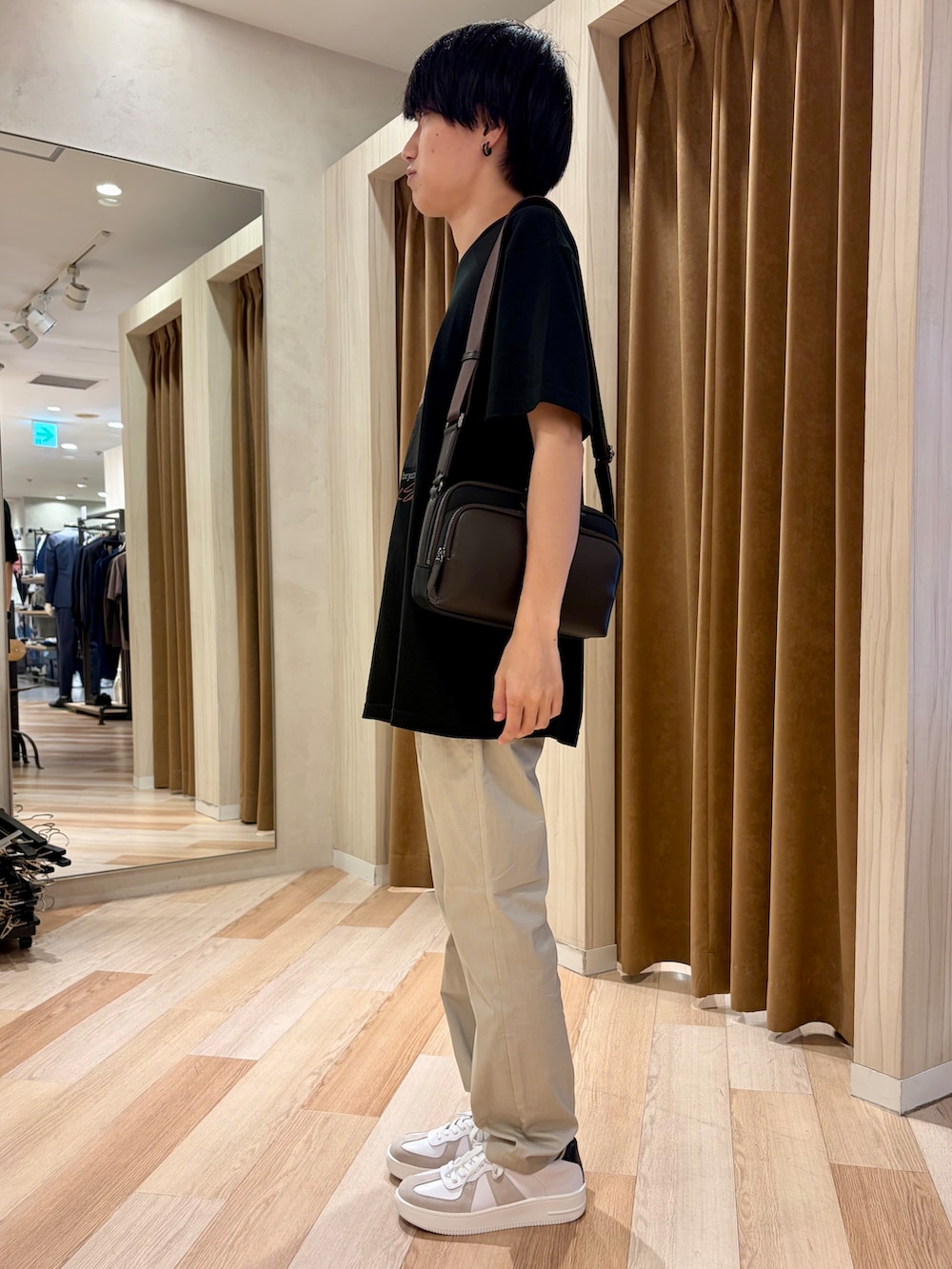 ブラック系のTシャツ/カットソー、ベージュ系のスラックス、ホワイト系のスニーカーを着用したメンズの夏コーディネートの2枚目の写真