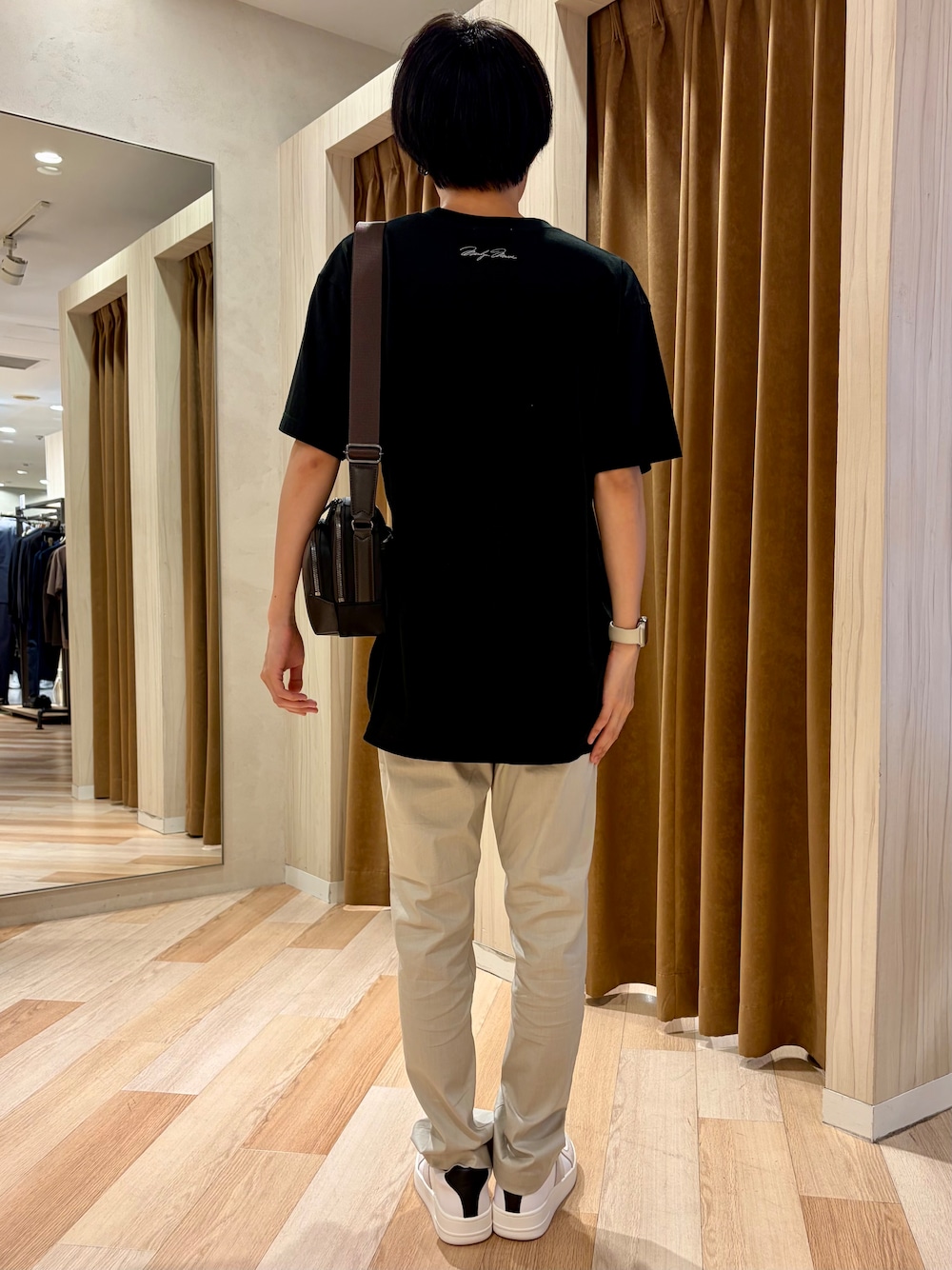 ブラック系のTシャツ/カットソー、ベージュ系のスラックス、ホワイト系のスニーカーを着用したメンズの夏コーディネートの3枚目の写真