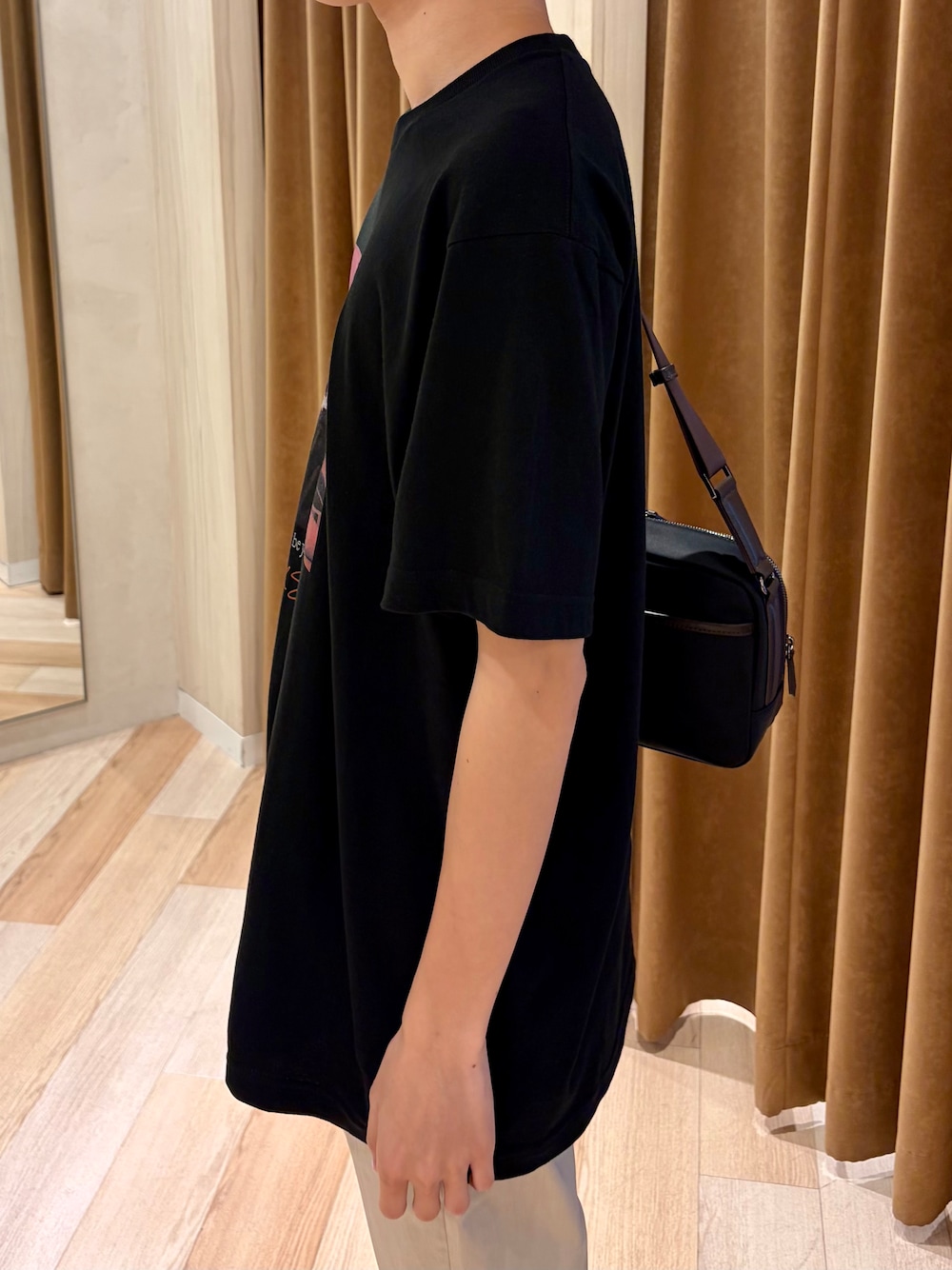 ブラック系のTシャツ/カットソー、ベージュ系のスラックス、ホワイト系のスニーカーを着用したメンズの夏コーディネートの5枚目の写真