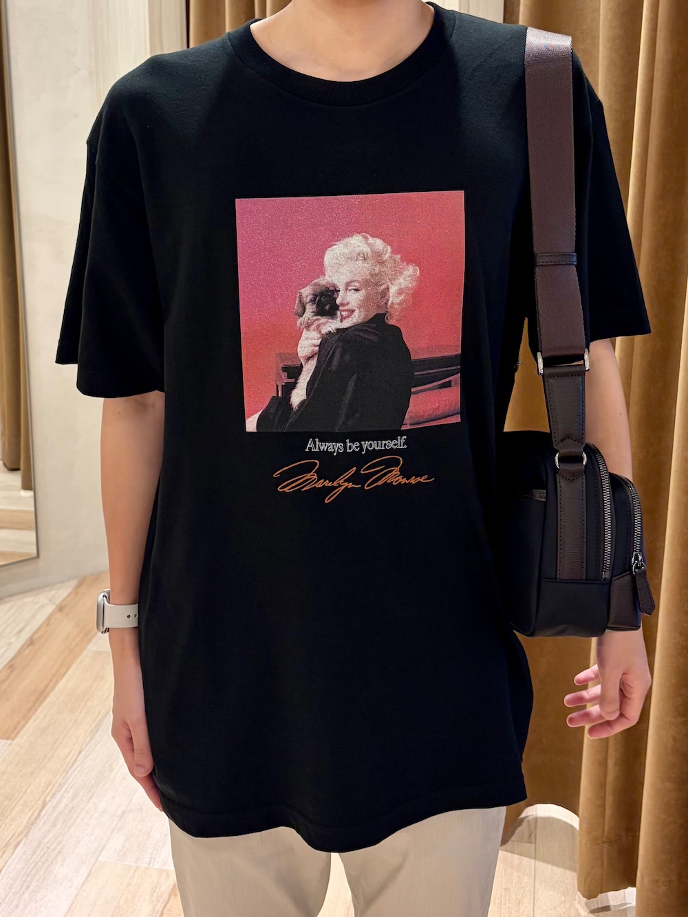 ブラック系のTシャツ/カットソー、ベージュ系のスラックス、ホワイト系のスニーカーを着用したメンズの夏コーディネートの4枚目の写真