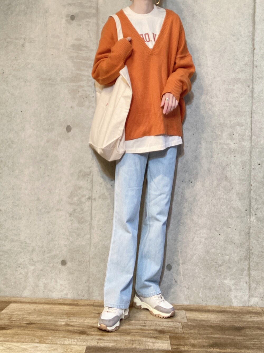 ブラック系のダウンジャケット/コート、オレンジ系のニット/セーター、ベージュ系のTシャツ/カットソーを着用したレディースの冬コーディネートの2枚目の写真