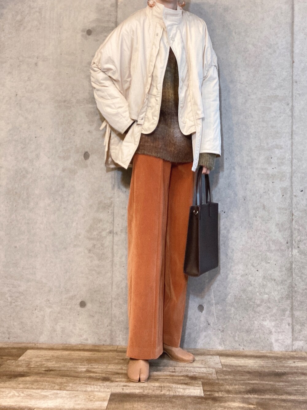 ホワイト系のダウンジャケット/コート、グリーン系のニット/セーター、オレンジ系のその他パンツを着用したレディースの冬コーディネートの3枚目の写真