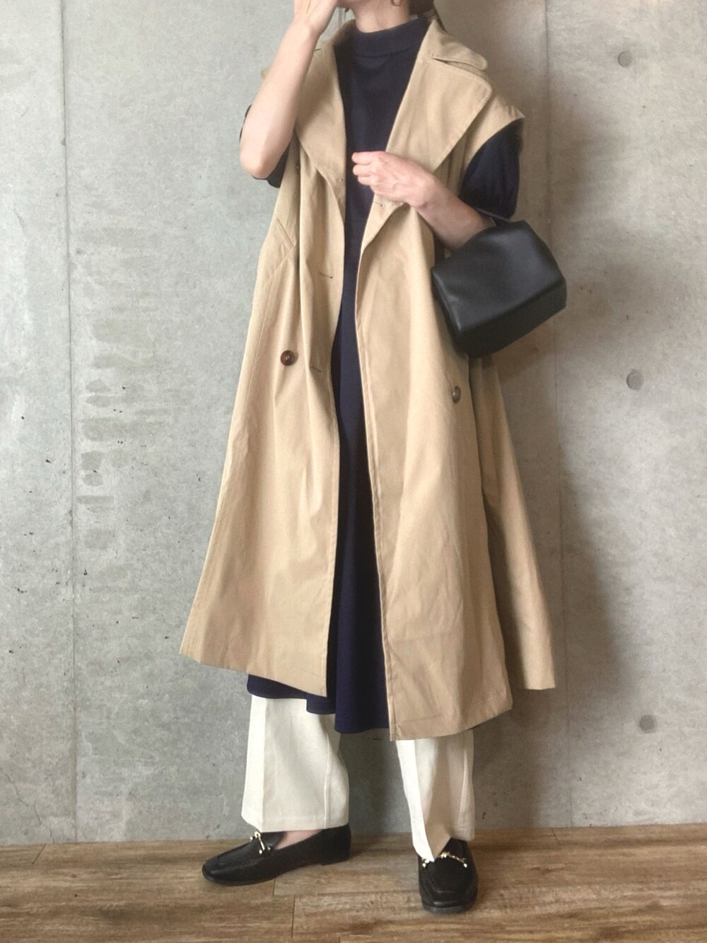 ベージュ系のトレンチコート、ブラック系のショルダーバッグ、ホワイト系のスラックスを着用したレディースの春コーディネートの2枚目の写真