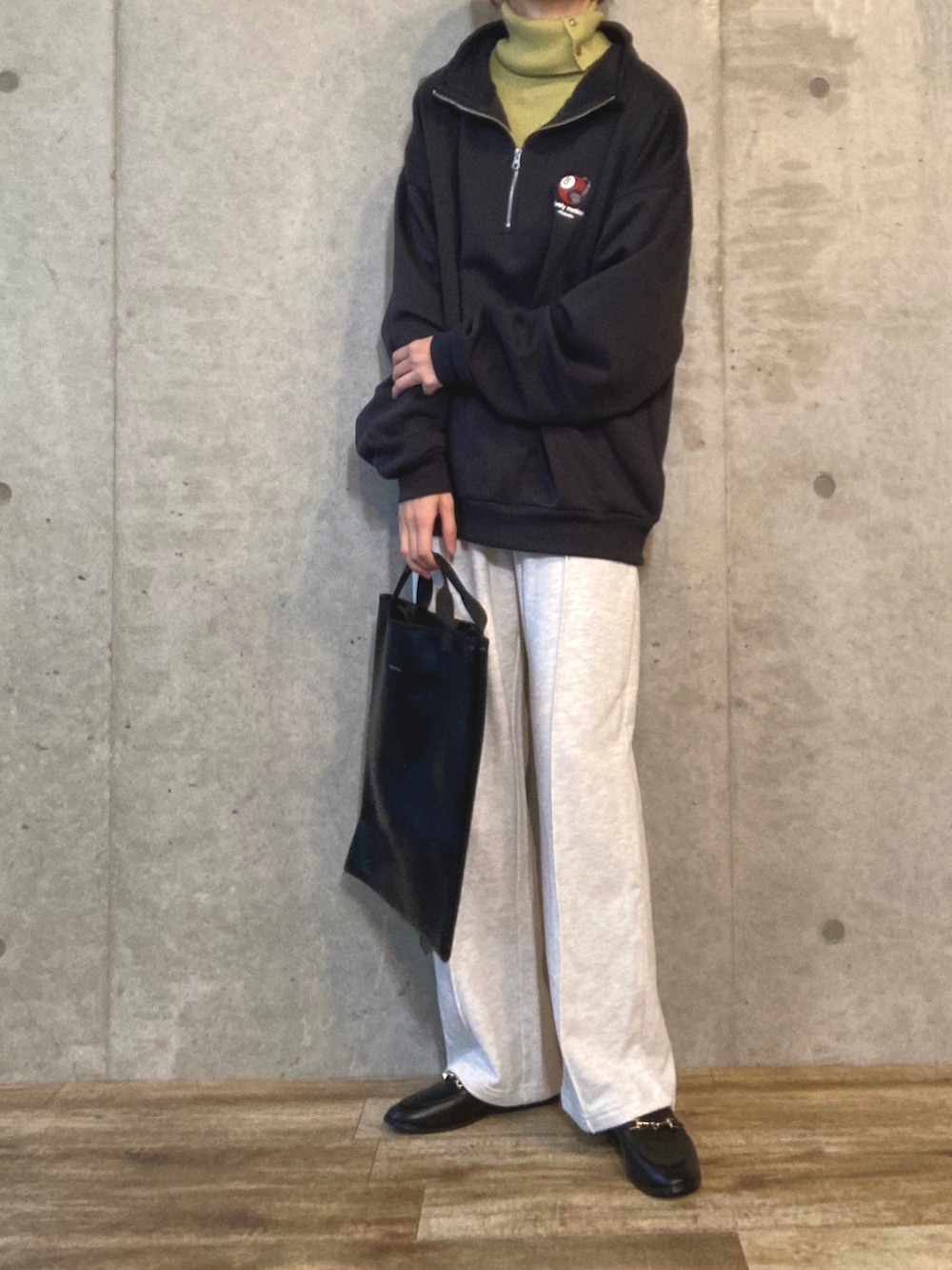 グレー系のスウェット、グリーン系のニット/セーター、ベージュ系のスウェットパンツを着用したレディースの秋コーディネートの2枚目の写真