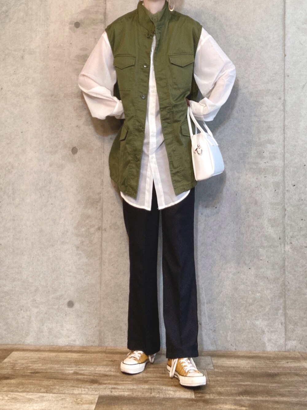 ホワイト系のシャツ/ブラウス、グリーン系のベスト、ブラウン系のトートバッグを着用したレディースの春コーディネートの2枚目の写真