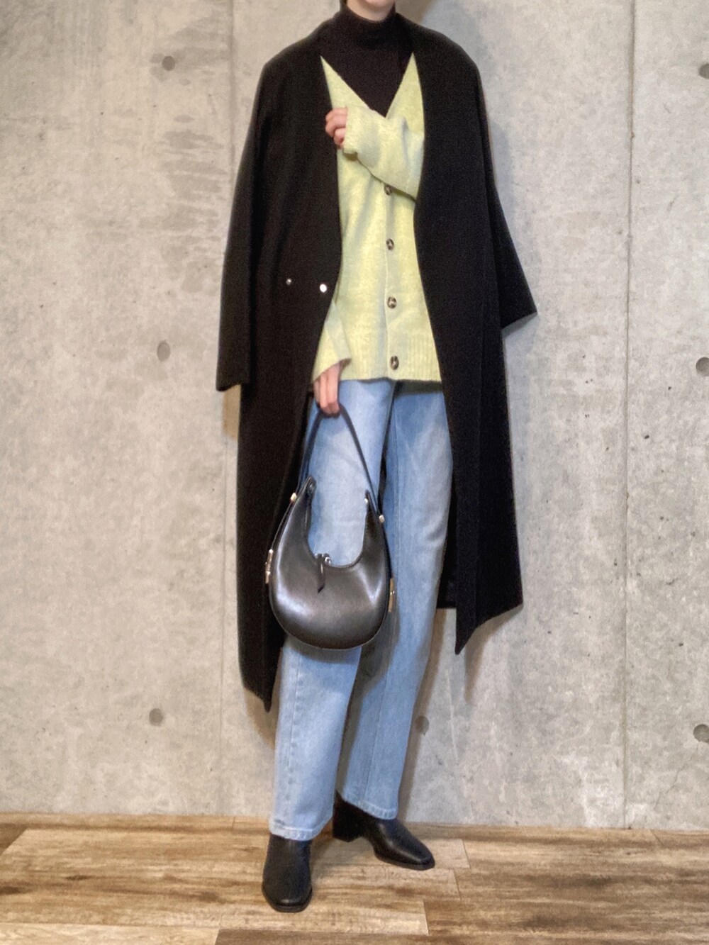 ブラック系のニット/セーター、ブラック系のハンドバッグ、ブルー系のデニムパンツを着用したレディースの冬コーディネートの3枚目の写真