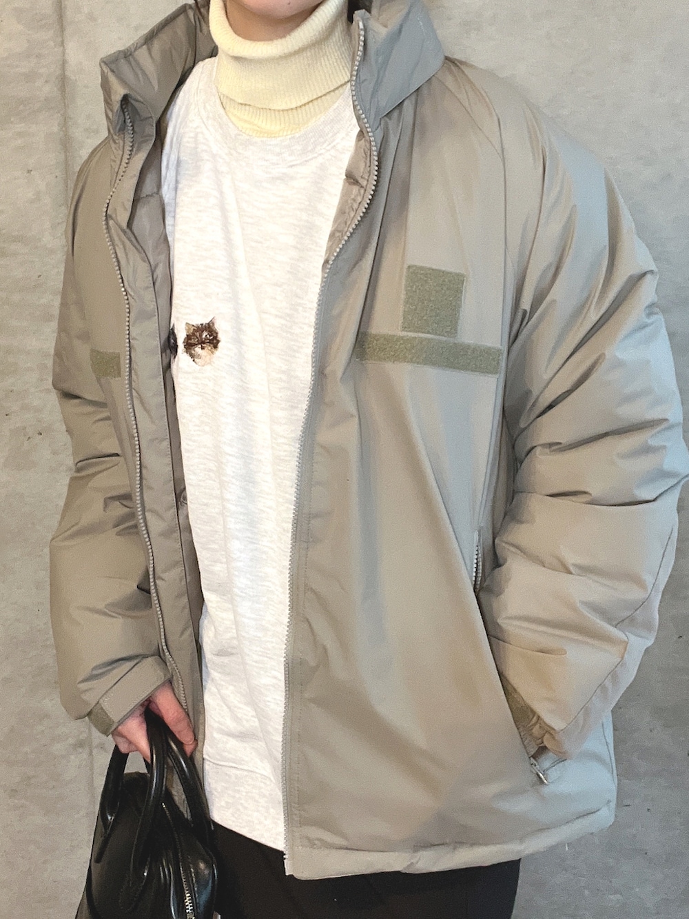 グリーン系のダウンジャケット/コート、ベージュ系のスウェット、ブラック系のショルダーバッグを着用したレディースの冬コーディネートの3枚目の写真