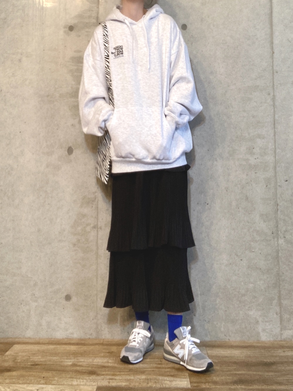 グレー系のパーカー、その他のトートバッグ、ブラック系のスカートを着用したレディースの秋コーディネートの2枚目の写真