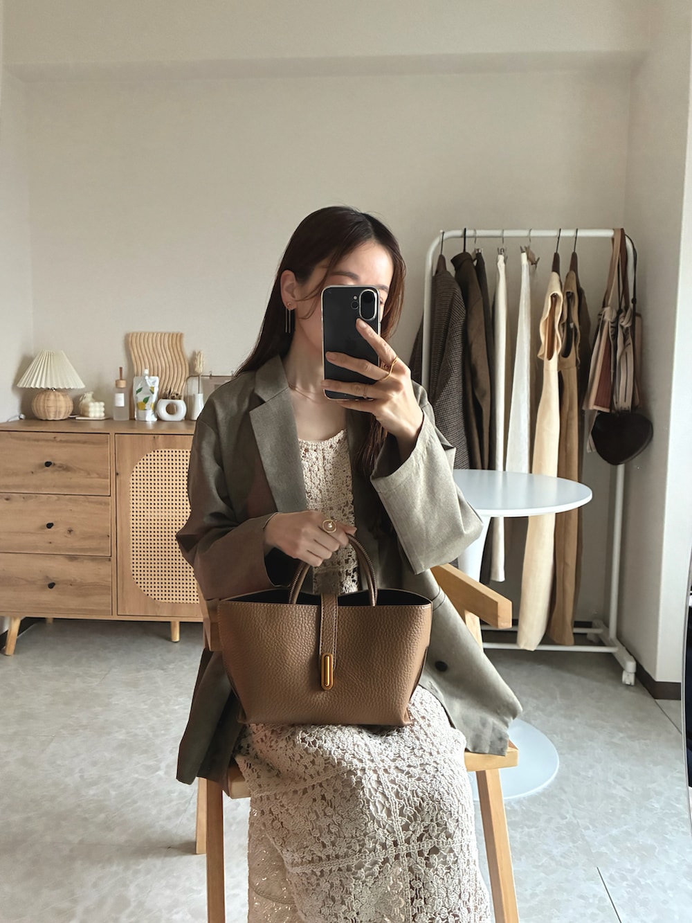 ベージュ系のテーラードジャケット、ホワイト系のワンピース、ブラウン系のハンドバッグを着用したレディースの春コーディネートの2枚目の写真