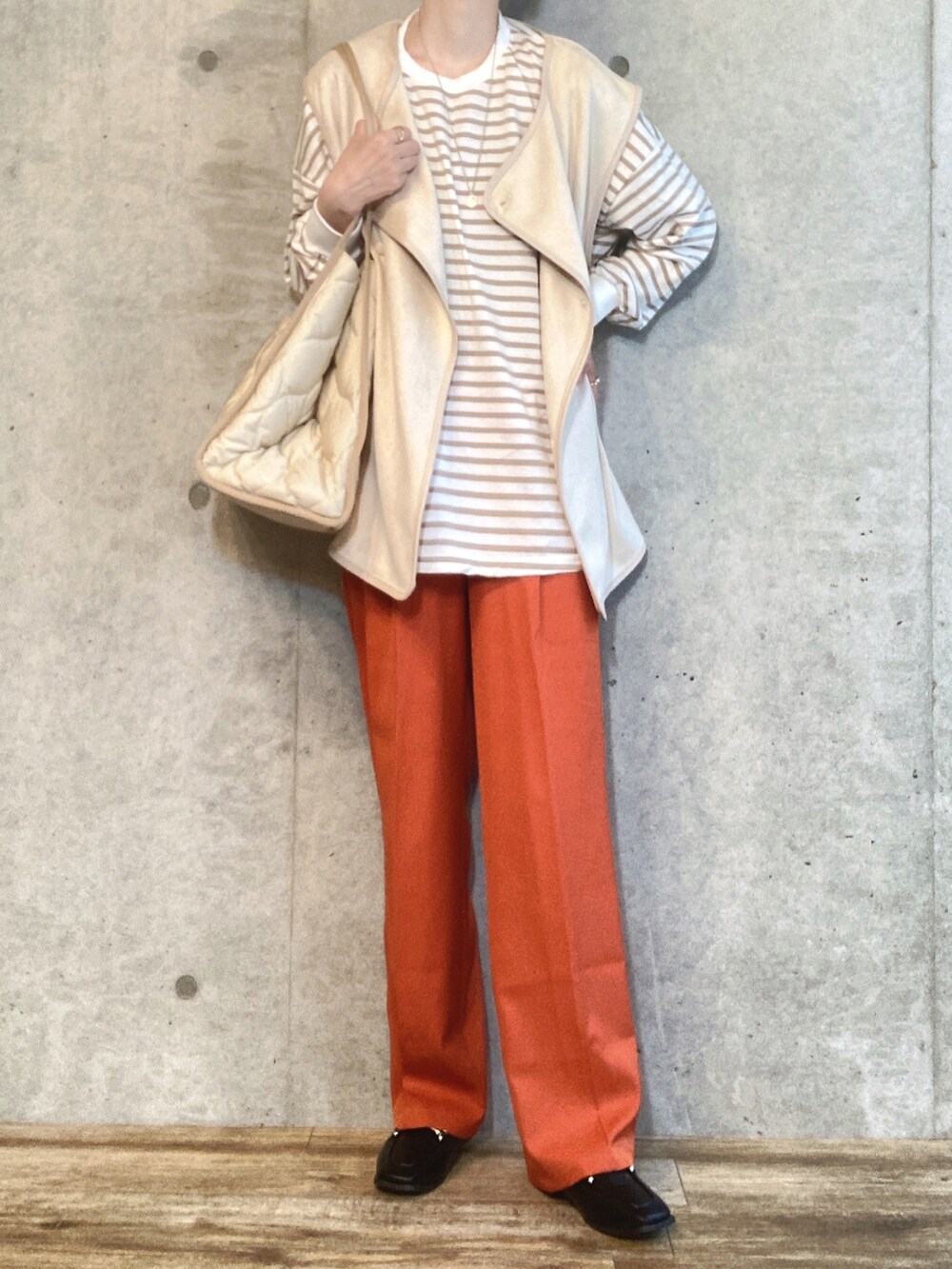 ホワイト系のベスト、ベージュ系のTシャツ/カットソー、ホワイト系のトートバッグを着用したレディースの秋コーディネートの2枚目の写真