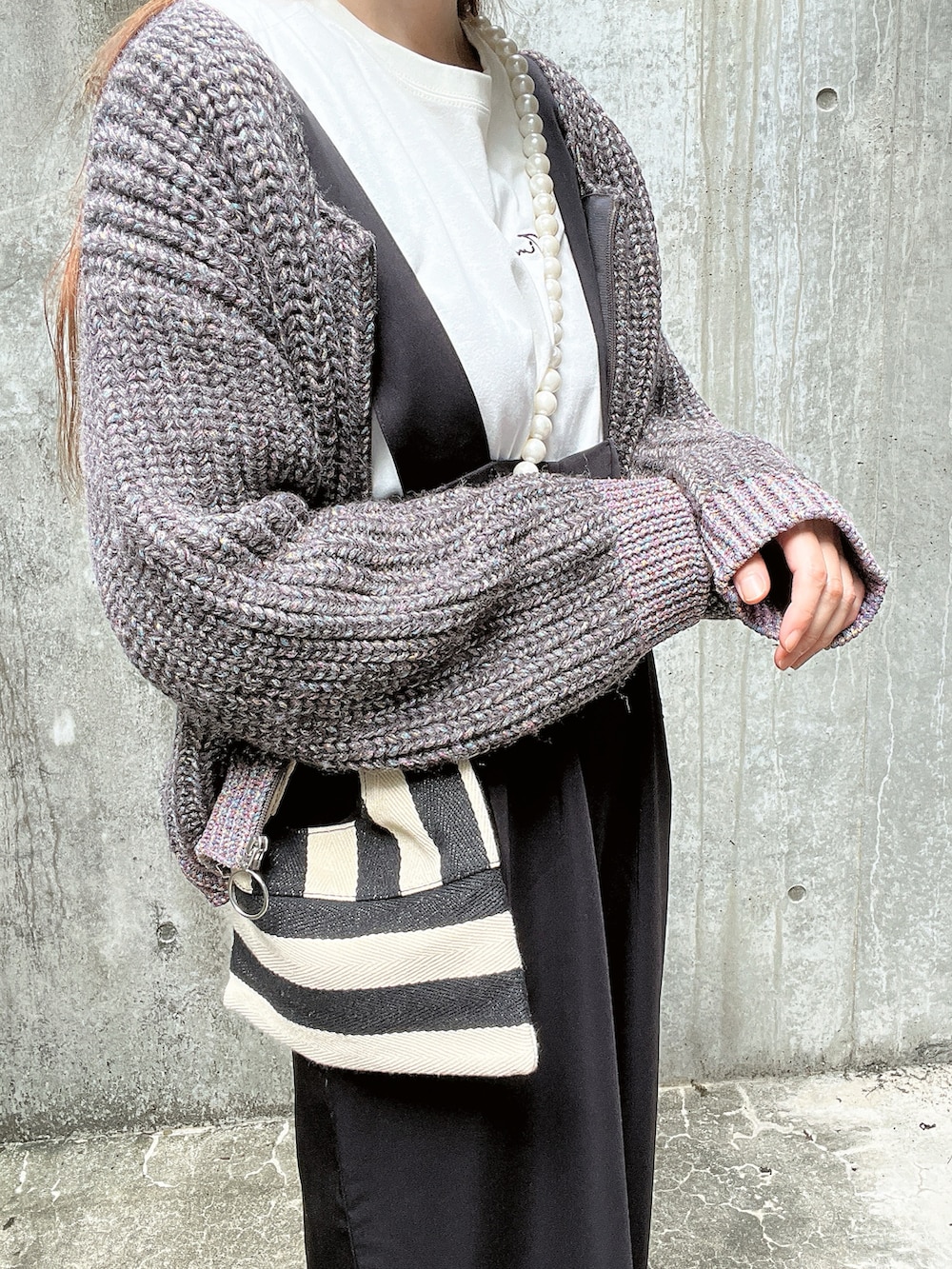 グレー系のニット/セーター、ホワイト系のTシャツ/カットソー、ホワイト系のショルダーバッグを着用したレディースの秋コーディネートの5枚目の写真